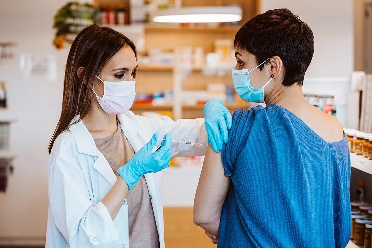 Pielęgniarka podaje kobiecie szczepionkę