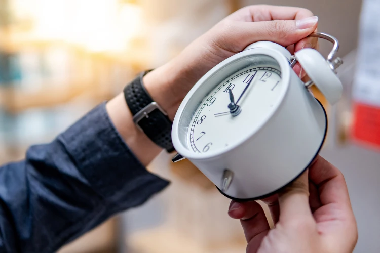 Zdjęcie ręki trzymającej budzik.