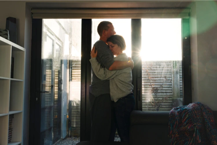 Zdjęcie smutnej pary, która przytula się na stojąco.