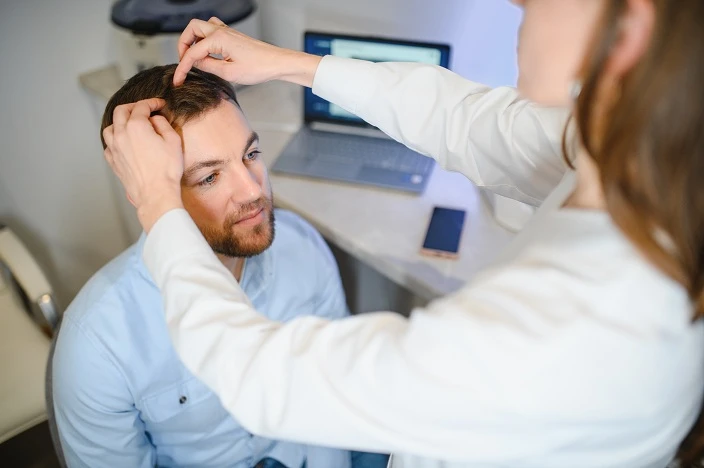 lekarz sprawdza skórę głowy pacjenta