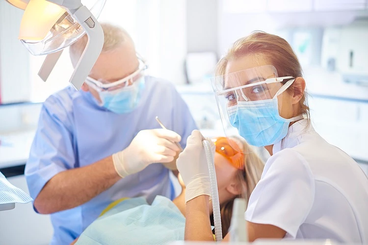 Lekarz dentysta i asystentka podczas leczenia stomatologicznego pacjentki