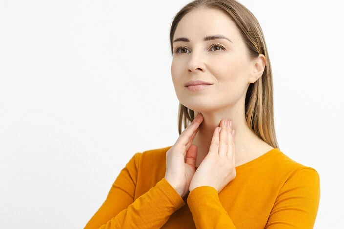 kobieta dotyka dłońmi swoją szyje