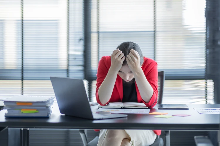 Zmęczona kobieta w pracy z pochyloną głową nad laptopem