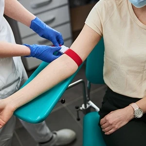 Pielęgniarka zaciska stazę na ramieniu pacjentki przed pobraniem krwi