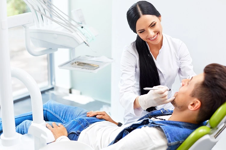 Uśmiechnięta higienistka stomatologiczna podczas leczenia pacjenta