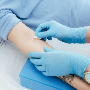 Pielęgniarka odkażająca ramię pacjentki przed pobraniem krwi