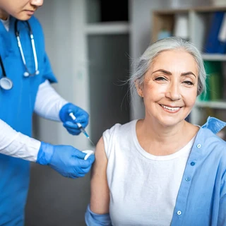 Uśmiechnięta kobieta otrzymuje zastrzyk ze szczepionką