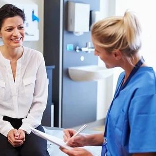 Lekarka zadaje pytania pacjentce w gabinecie. 