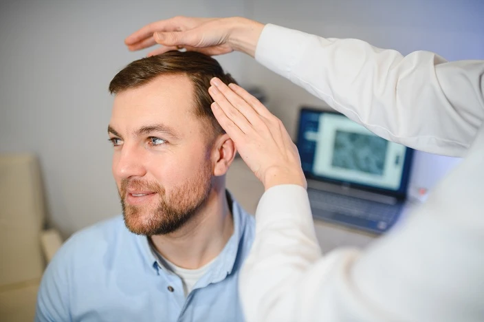 Lekarz bada skórę głowy pacjenta 