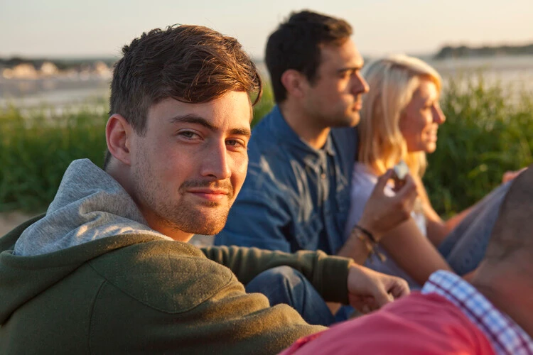 Mężczyzna siedzący ze znajomymi na świeżym powietrzu