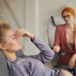 Kobieta na fotelu podczas sesji z psychologiem na temat leczenia bezsenności.
