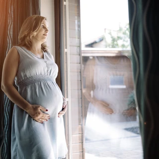 Zamyślona kobieta w ciąży borykająca się z problemami psychicznymi.