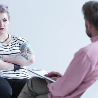 Młoda, zmartwiona kobieta siedząca na fotelu podczas sesji terapii DDA.