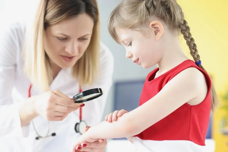 Pediatra ogląda przez lupę rękę dziewczynki