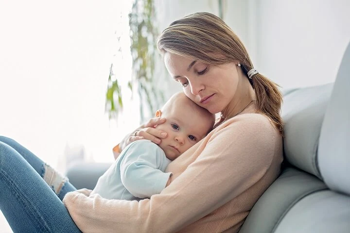 Kobieta siedzi na kanapie i przytula dziecko