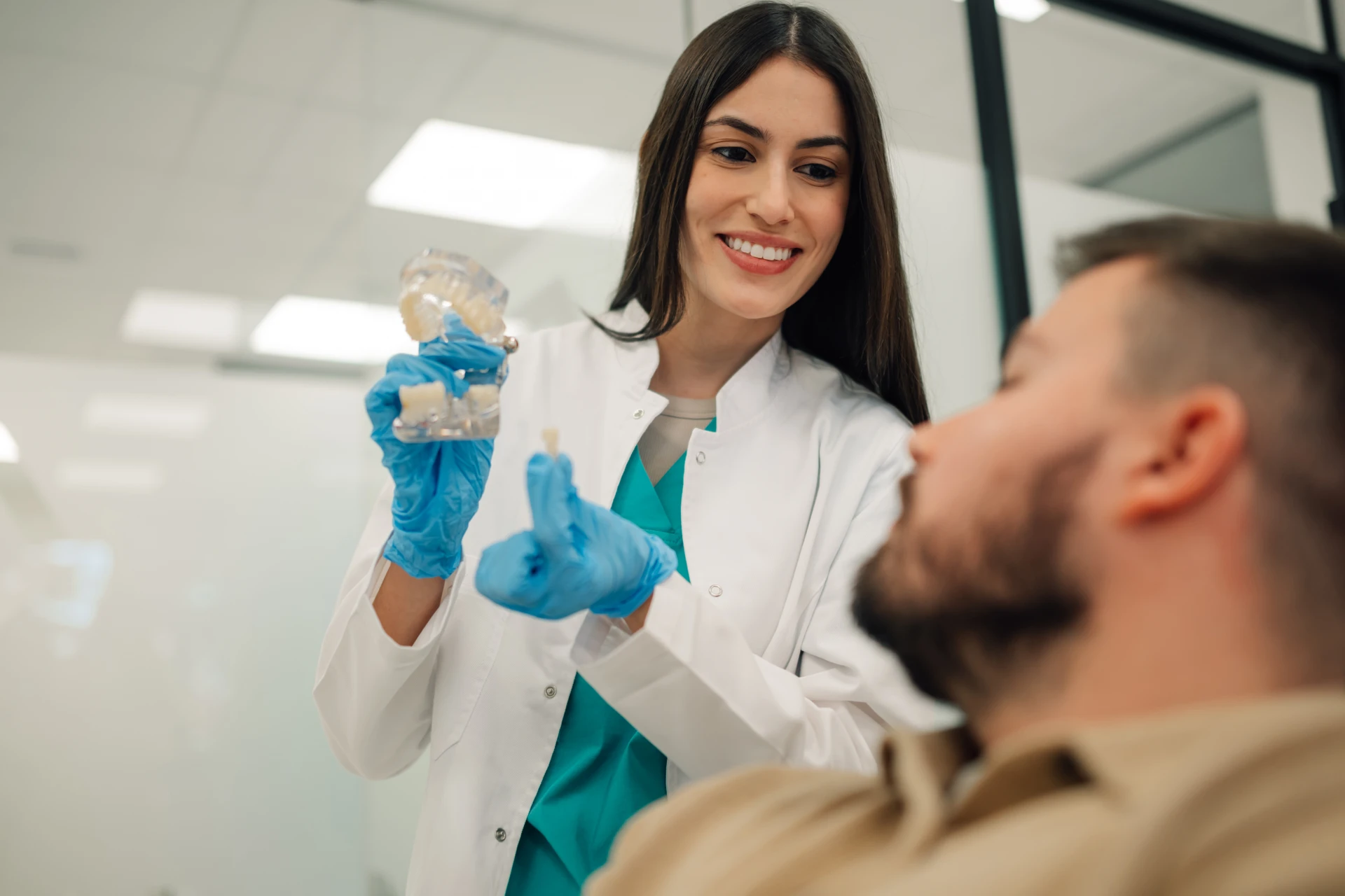 Dentystka pokazuje pacjentowi model licówki na zęby