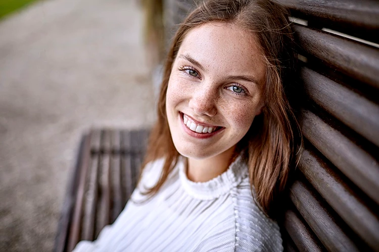 Młoda kobieta siedzi na ławce i uśmiecha się
