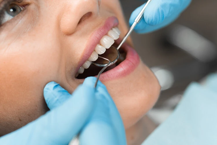 Zbliżenie na uśmiechniętą kobietę w trakcie wizyty u dentysty