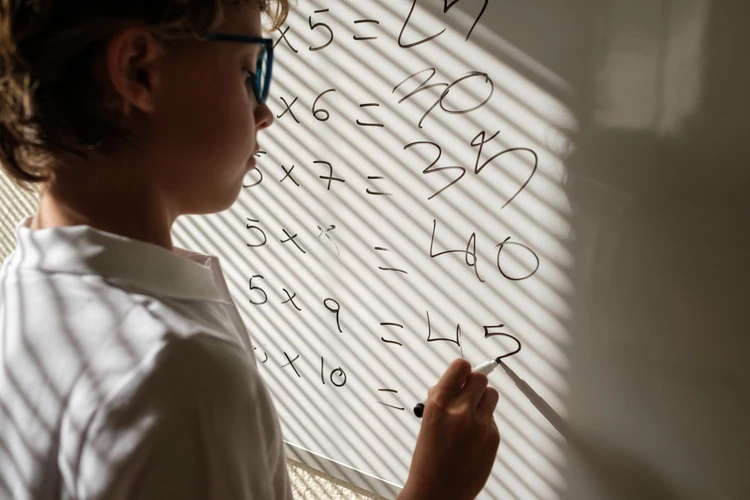 : Chłopiec piszący obliczenia na tablicy