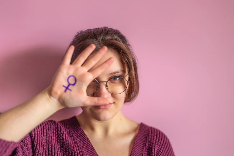 Kobieta pokazująca dłoń z namalowanym symbolem płci kobiet