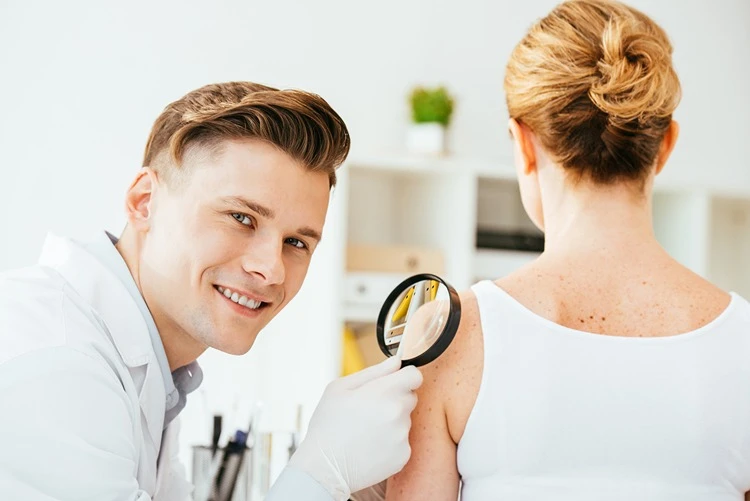 Dermatolog ogląda pieprzyk na ciele kobiety