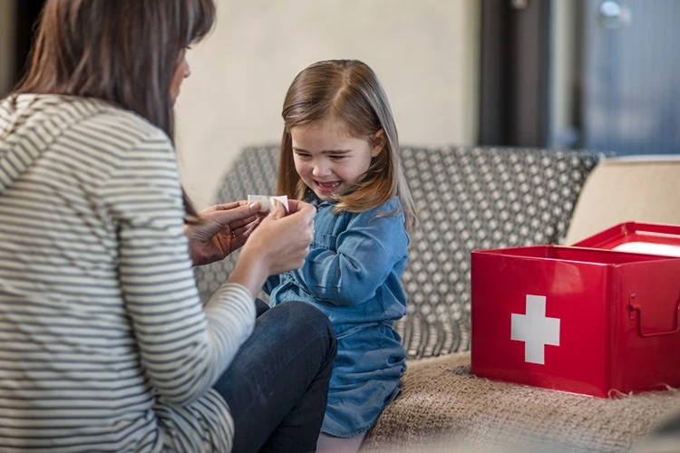 Mama przyklejająca plaster na skaleczony palec córki